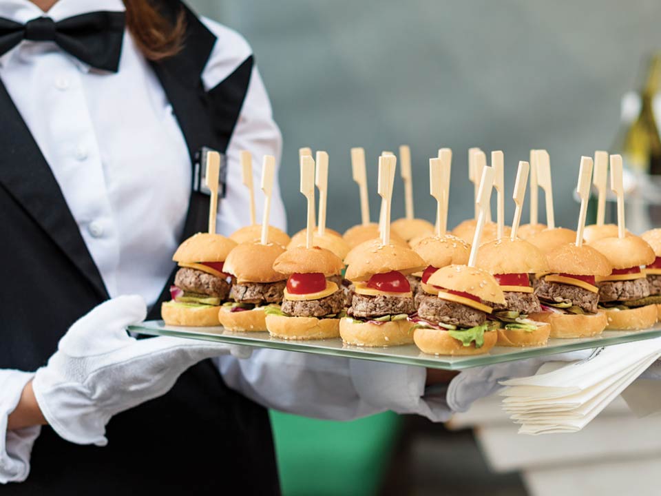 A catering waitress carrying sliders