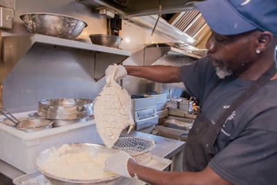 A cook prepares hand-breaded flounder at Hyman's Seafood