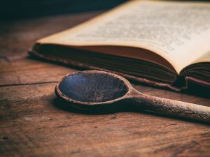 old cookbook and a well-worn wooden spoon