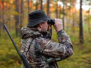 A hunter unsing a pair of binoculars to scout out a location